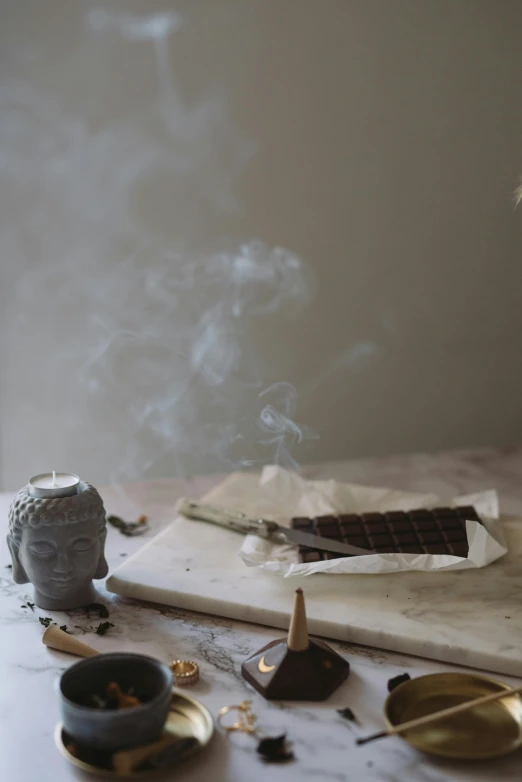 a wooden cutting board sitting on top of a table, a still life, incense smoke fills the air, chocolate, white marble interior photograph, figure meditating close shot
