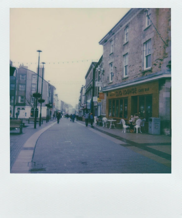 a group of people walking down a street next to tall buildings, a polaroid photo, old town, in muted colours, laura watson, town square