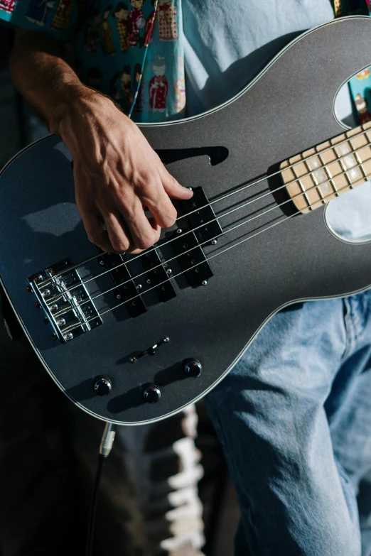 a close up of a person holding a guitar, steel gray body, bass, zoomed in