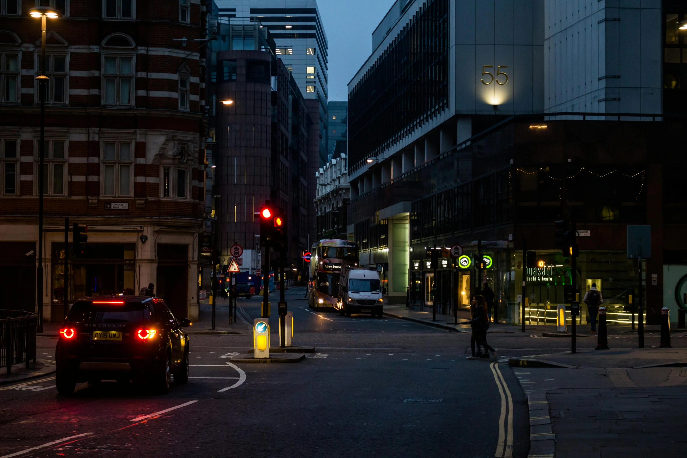 a car driving down a street next to tall buildings, by Jay Hambidge, pexels contest winner, gas lamps, london bus, poorly lit, square