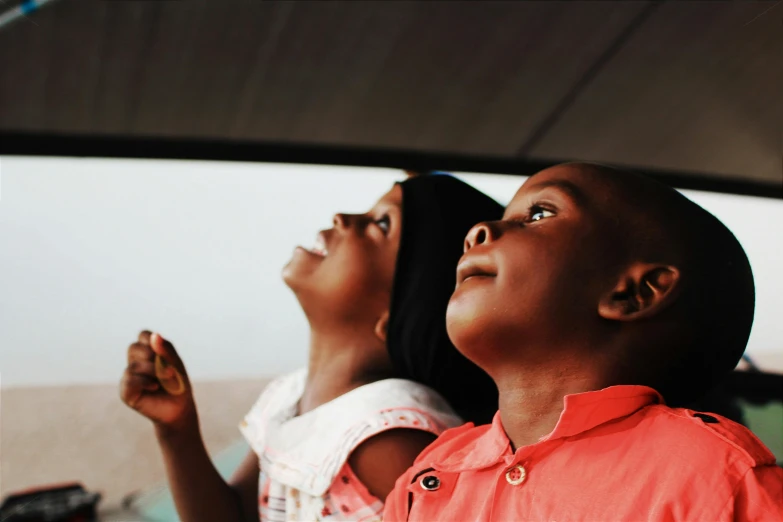 a couple of kids standing next to each other, pexels contest winner, visual art, men look up at the sky, looking out the window, dark-skinned, a still of a happy