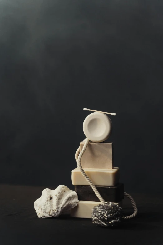 a stack of books sitting on top of a table, an abstract sculpture, inspired by Isamu Noguchi, unsplash, carved soap, rope, 4k polymer clay food photography, square masculine jaw