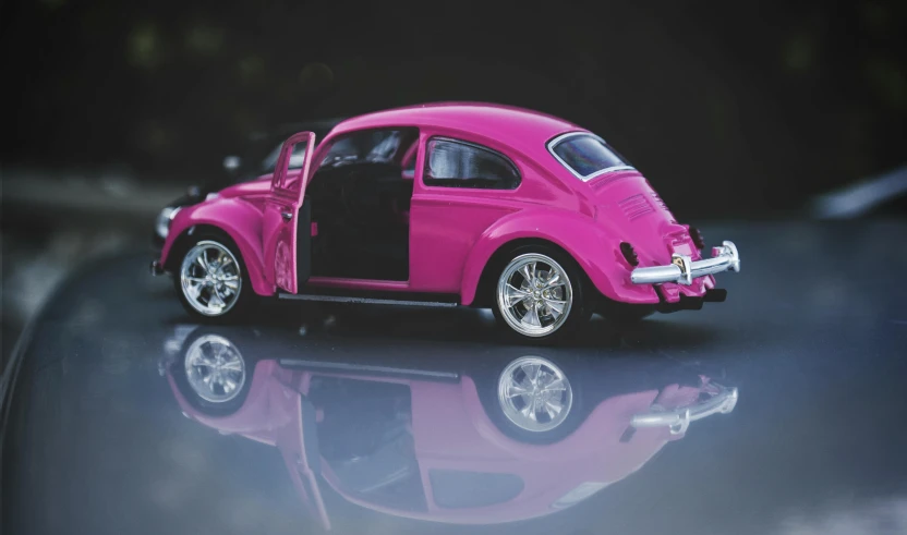 a pink toy car sitting on top of a table, by Lee Loughridge, pexels contest winner, photorealism, beetle, die - cast metal, reflecting, fuchsia