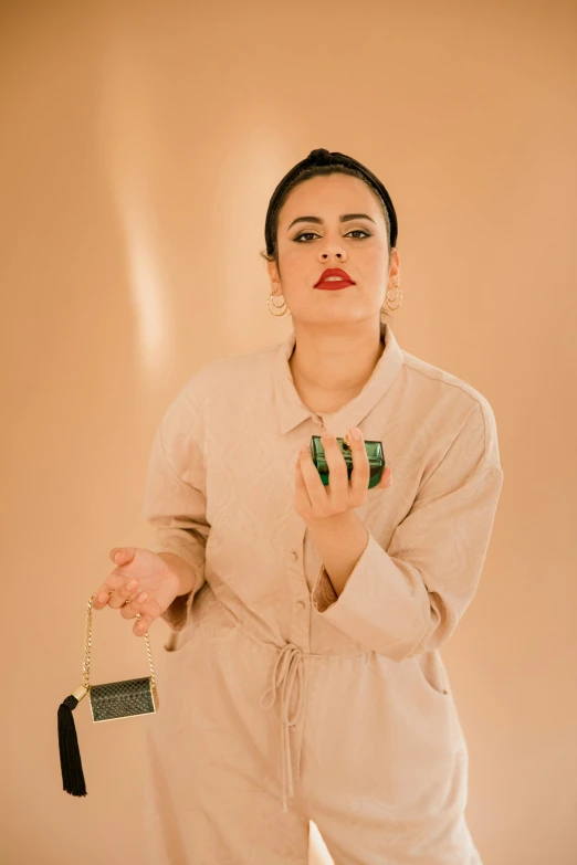 a woman in a white jumpsuit holding a purse, an album cover, by Olivia Peguero, wearing only a green robe, holding gold watch, - 9, makeup