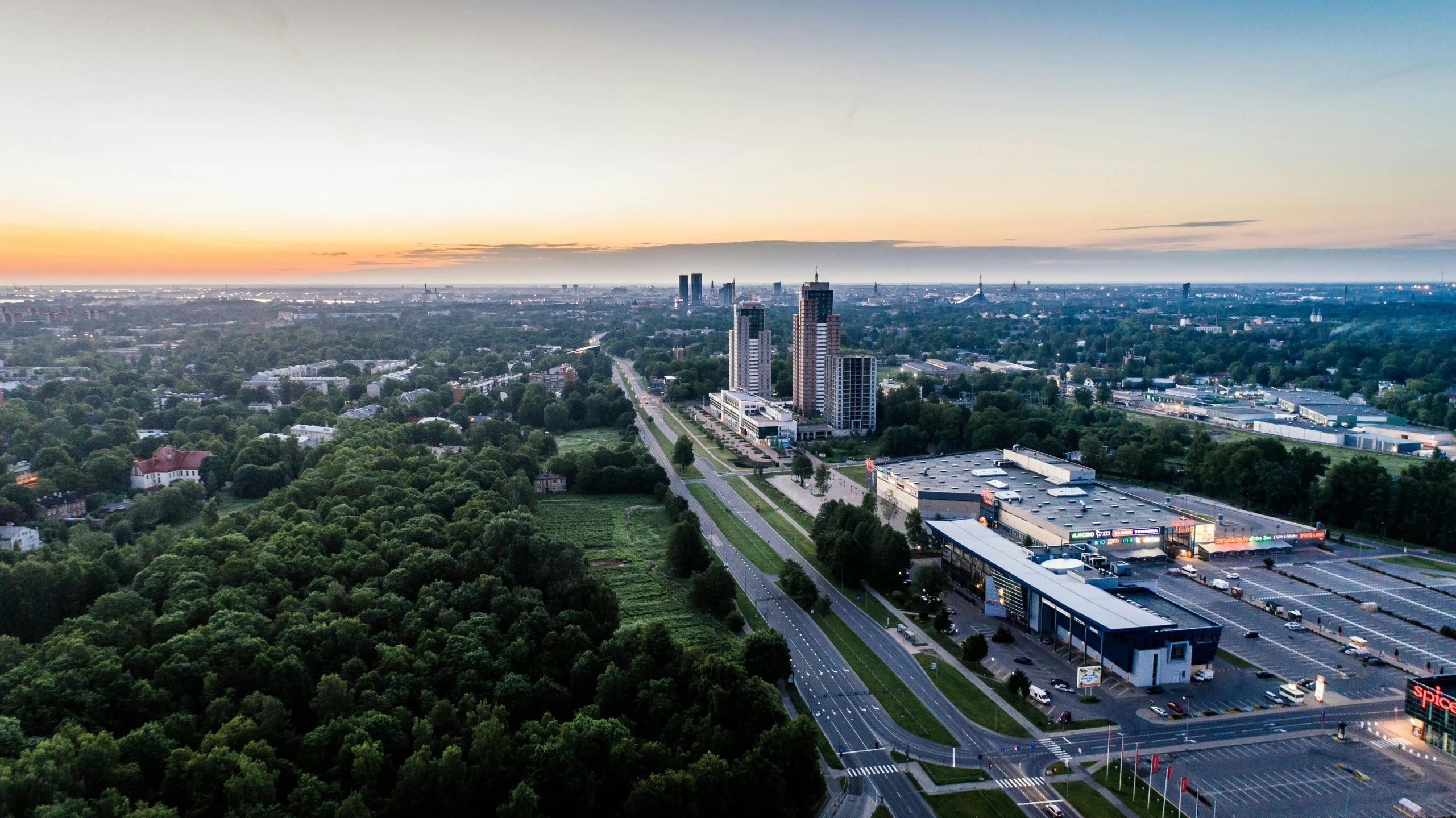 an aerial view of a city at sunset, by Adam Marczyński, pexels contest winner, hyperrealism, panorama view, capital of estonia, forest setting with skyscrapers, ultra hi resolution picture