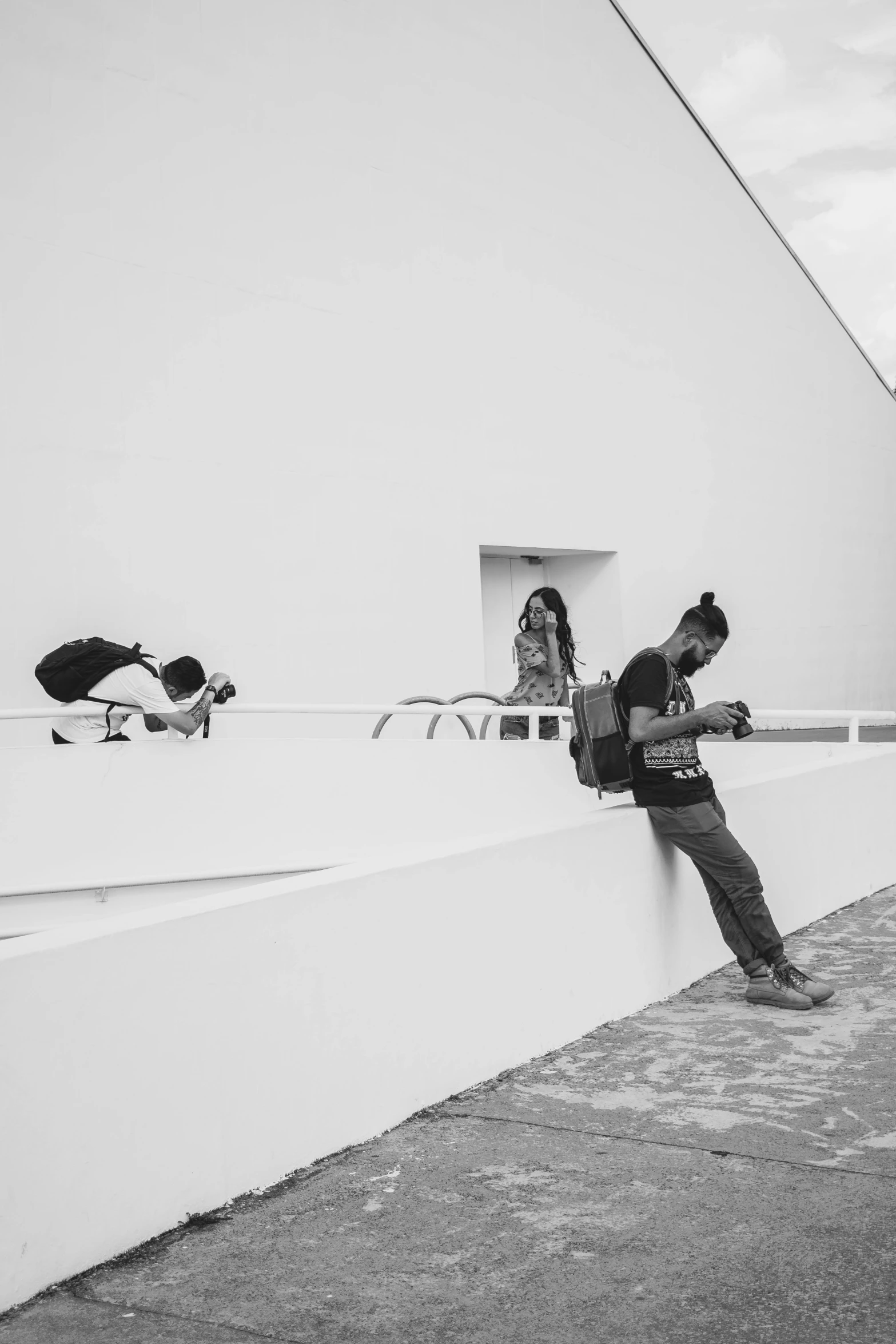 a black and white photo of a person leaning against a wall, a black and white photo, by Alexis Grimou, people watching around, taking selfies, oscar niemeyer, sittin