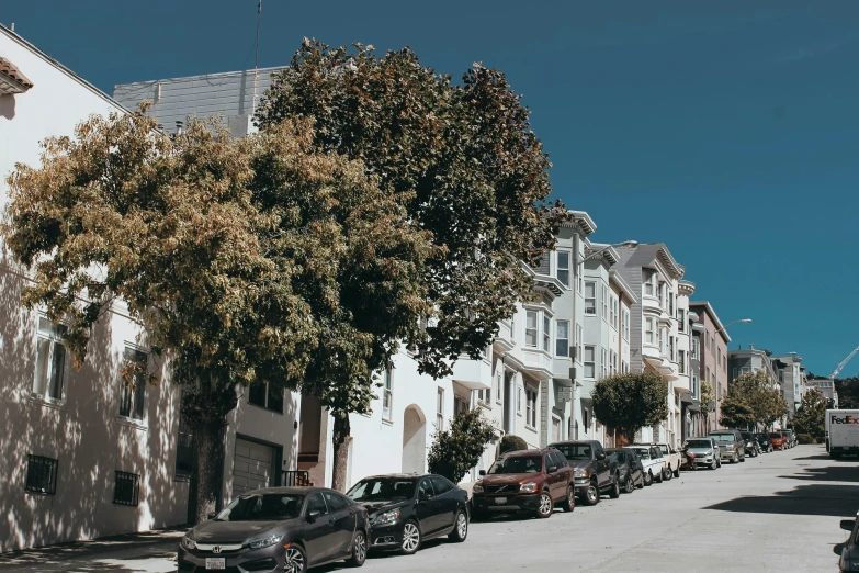 a row of parked cars on a city street, by Carey Morris, unsplash, built on a steep hill, bay area, maple trees along street, ignant