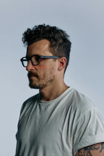 a man wearing glasses and a gray t - shirt, an album cover, by James Morris, unsplash, hyperrealism, short stubble, profile image, james jean and petra cortright, square rimmed glasses