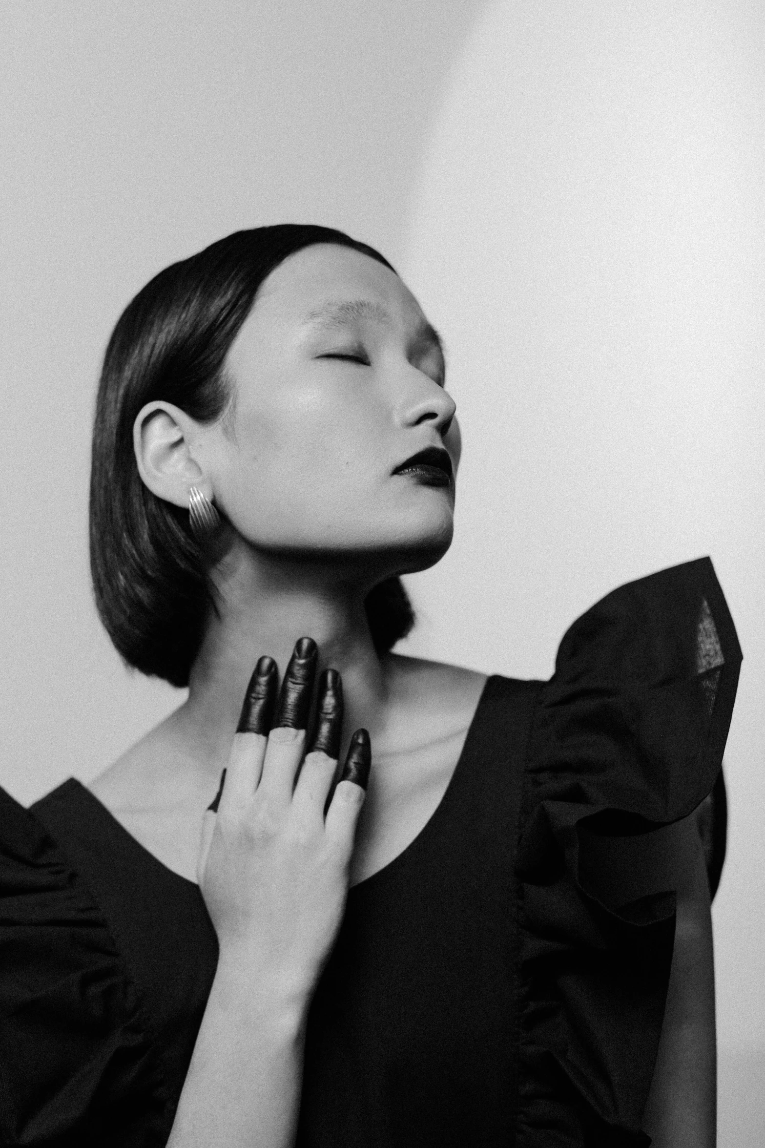 a black and white photo of a woman in a black dress, inspired by Gao Cen, black nails, bone jewellery, hong june hyung, wearing atsuko kudo latex outfit