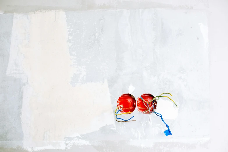 a red fire hydrant sitting on top of a white wall, a minimalist painting, inspired by Cerith Wyn Evans, unsplash, cherries, electric cables, plastic sea wrapped, glass orbs