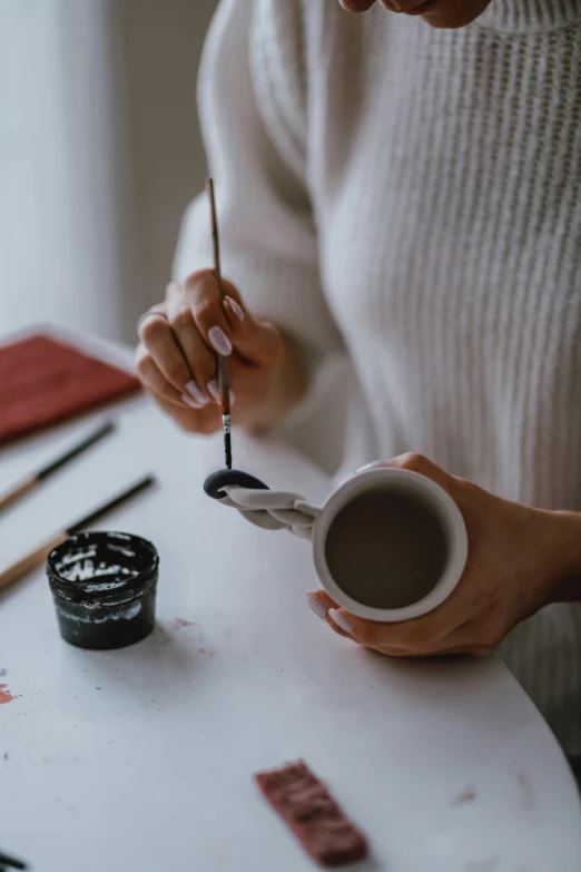 a woman sitting at a table with a cup of coffee, trending on pexels, process art, black paint, chinese ink brush, can of paint, gourmet and crafts