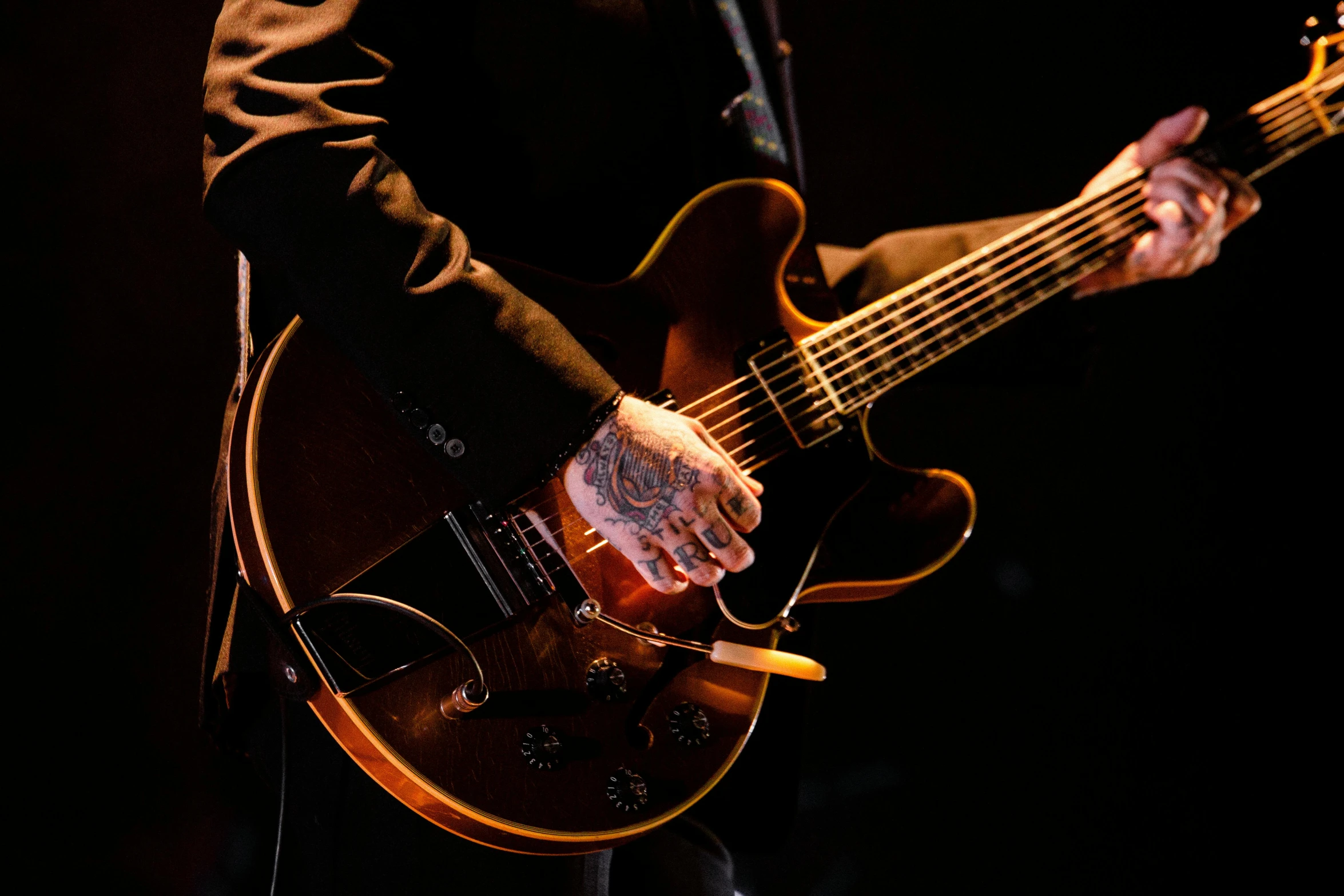 a close up of a person playing a guitar, an album cover, by Gavin Nolan, pexels contest winner, concert photo, tattooed, b. b king, sleek curves