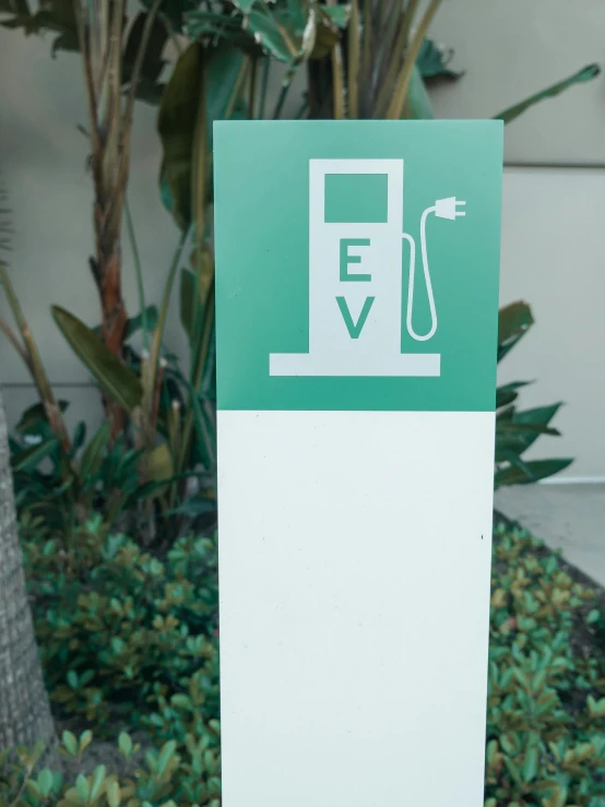 a green and white sign sitting next to a tree, charging plug in the chest, svg sticker, high detail shot, eva