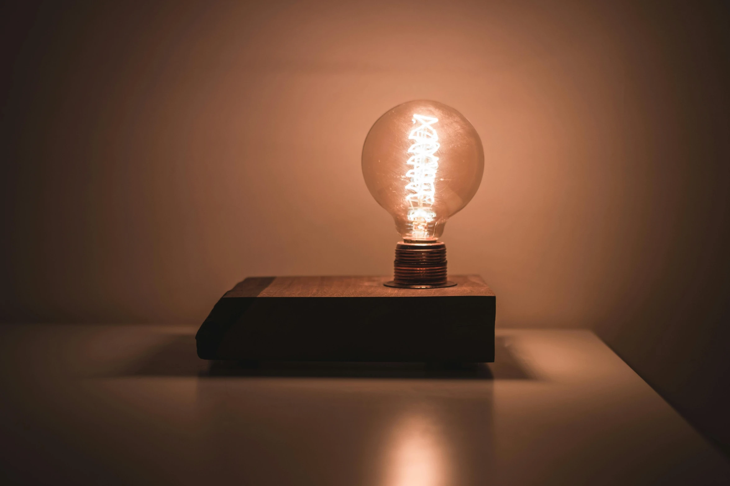 a light bulb sitting on top of a table, inspired by George Fiddes Watt, kinetic art, on a wooden plate, angled shot, magnetic, dark