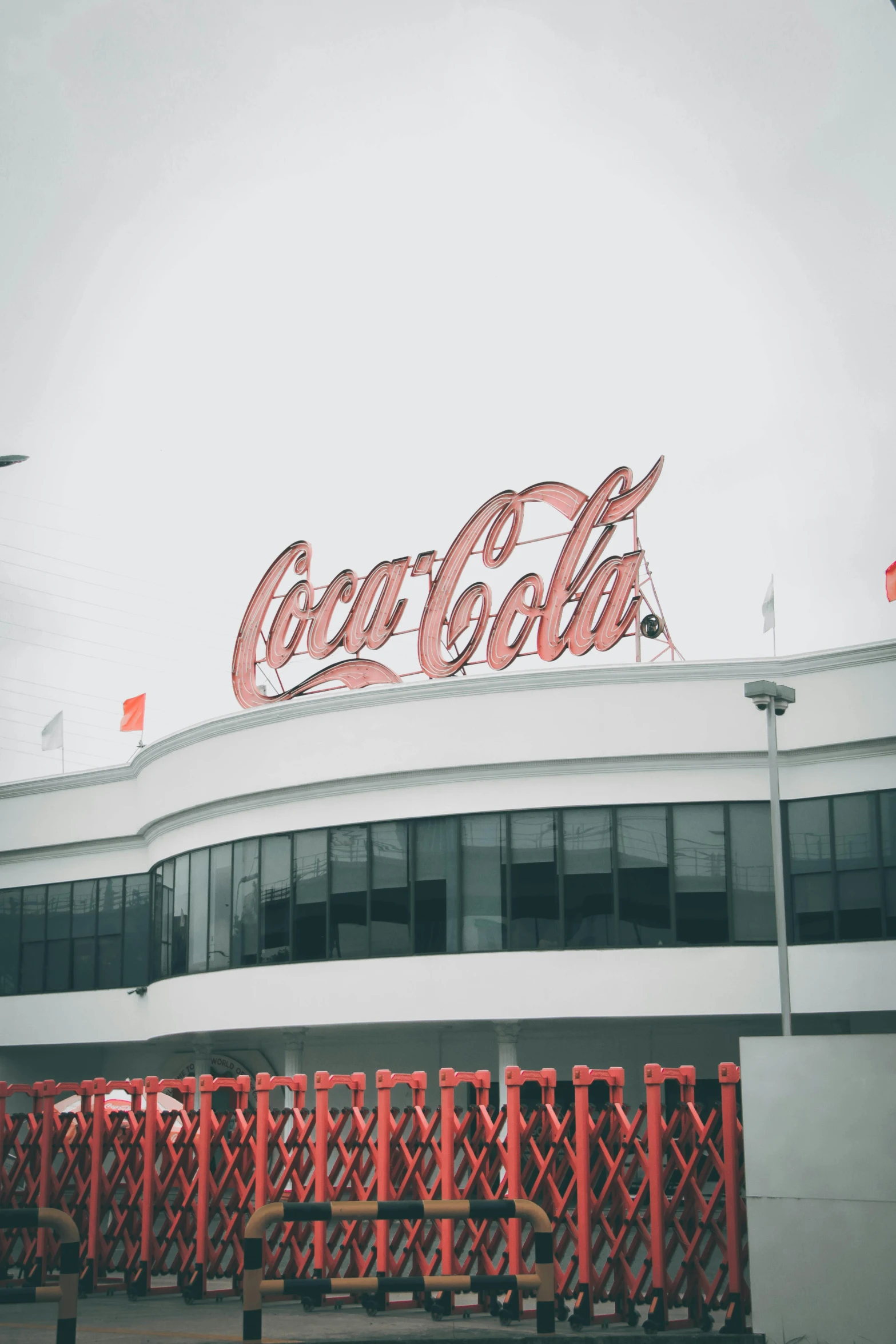 a building with a coca cola sign on top of it, inspired by Dorothy Coke, trending on unsplash, international typographic style, heaven!!!!!!!!, art deco stadium, nice slight overcast weather, low quality photo