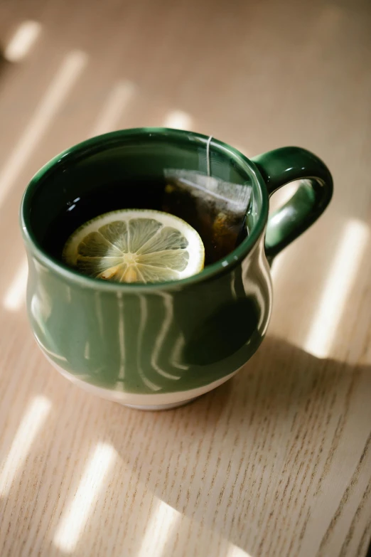 a cup of tea with a lemon slice in it, by Jessie Algie, pexels, dark green, made of glazed, ceramic, square