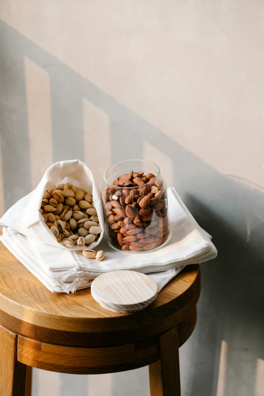 two bags of nuts sitting on top of a wooden table, a still life, unsplash, large jars on shelves, chile, sustainable materials, detailed product image