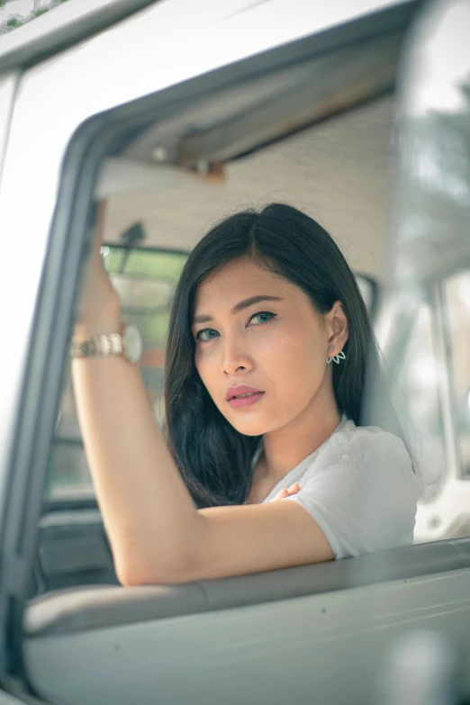 a woman sitting in the driver's seat of a car, by Basuki Abdullah, pexels contest winner, gemma chan girl portrait, square, handsome, van