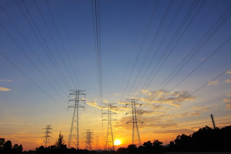 a sunset with power lines in the foreground, a picture, happening, getty images, fan favorite, power plants, orange and blue sky