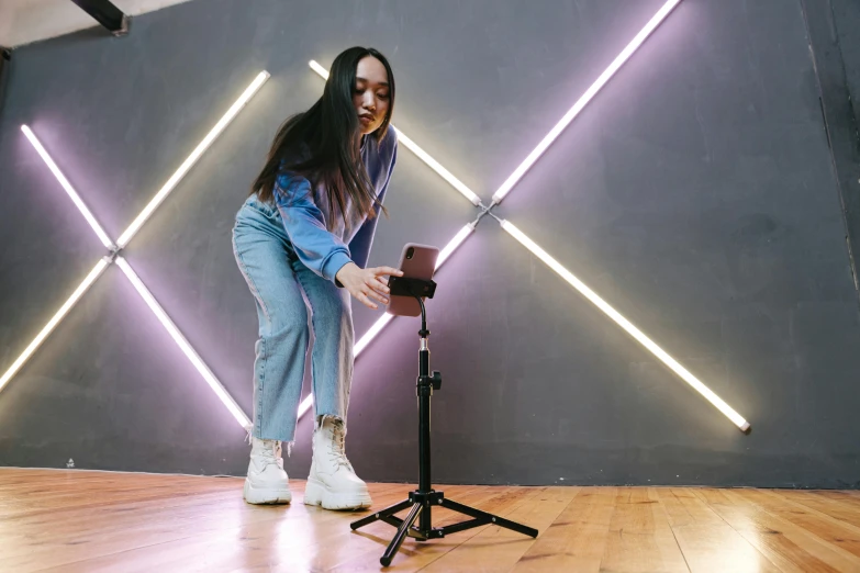 a woman standing in front of a camera on a tripod, a hologram, trending on pexels, interactive art, a young asian woman, phone recording, tall female emo art student, product introduction photo
