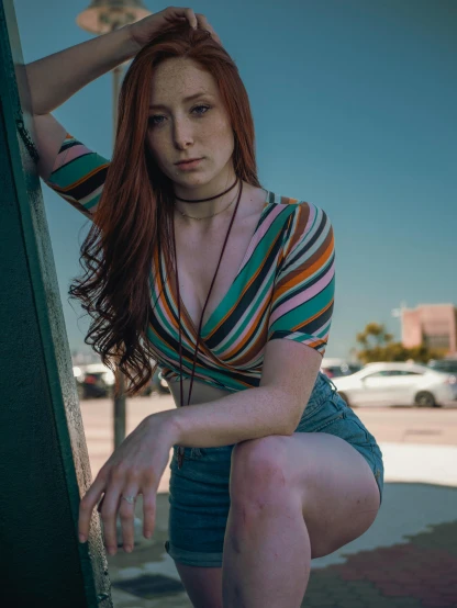 a woman with red hair leaning against a wall, a colorized photo, by Andrew Stevovich, pexels contest winner, dressed in a top and shorts, portrait of maci holloway, on a parking lot, taken with a canon eos 5d