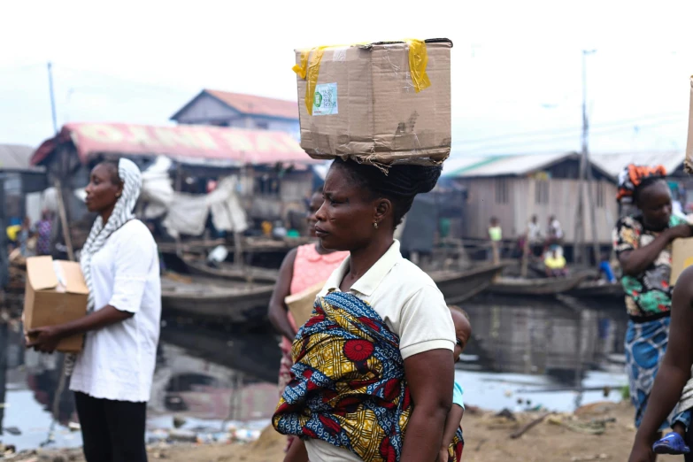 a woman carrying a box on her head, pexels contest winner, godwin akpan, market setting, thumbnail, unedited