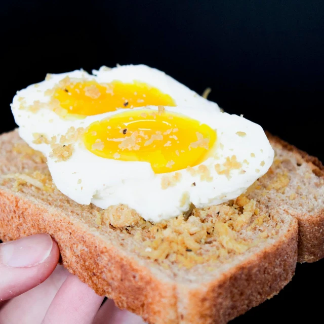 a person holding a piece of bread with an egg on it, listing image