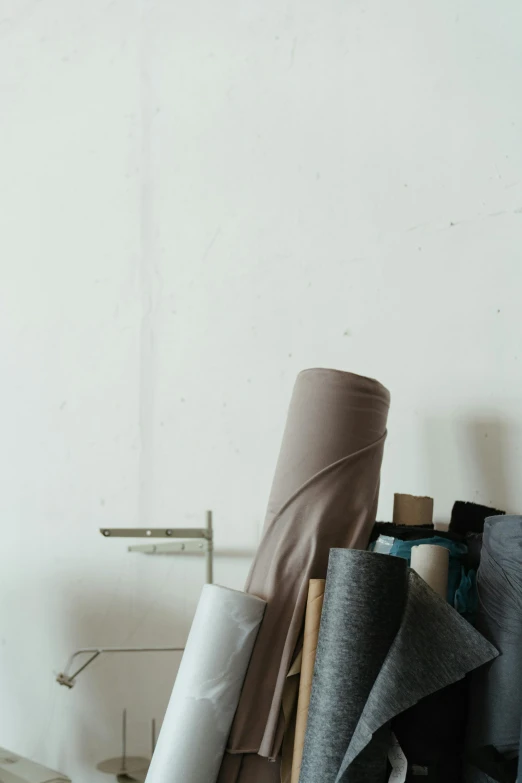 a bunch of rolls of fabric sitting on top of a table, by Carey Morris, unsplash, visual art, grey robes, stands at a his easel, but minimalist, brown