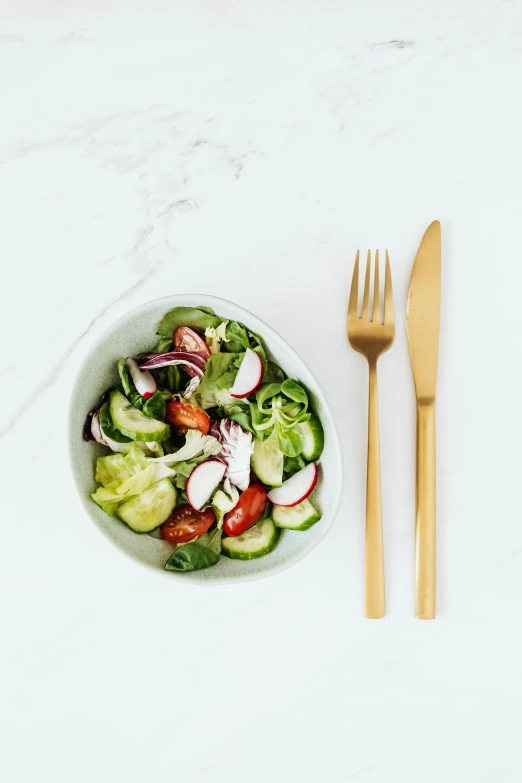 a bowl of salad next to a fork and knife, product image, curated collections, cucumber, front facing