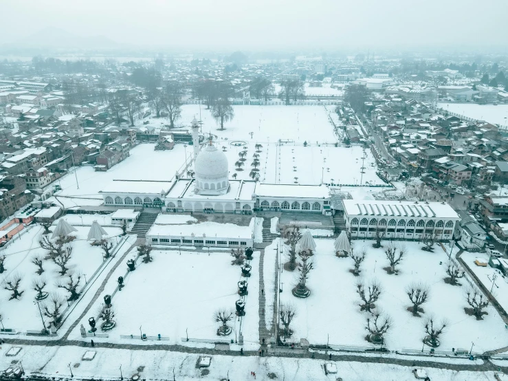 a large white building sitting on top of a snow covered field, by Bernardino Mei, pexels contest winner, islamic, aerial, college, during snowfall