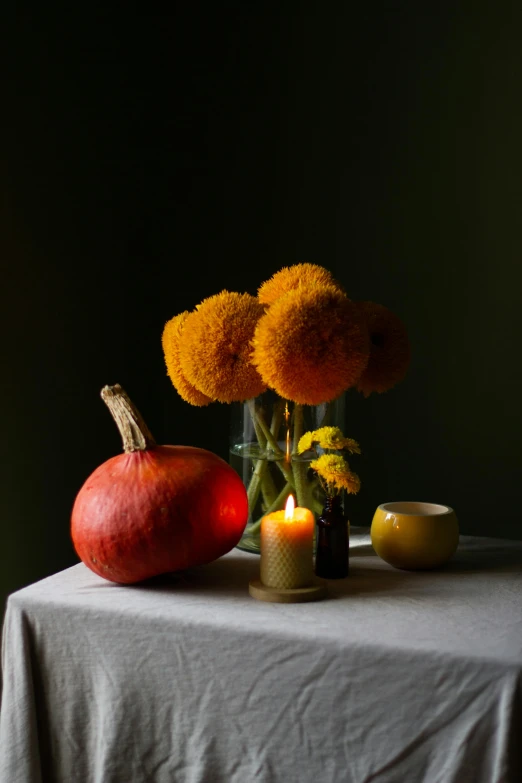 a table topped with a vase filled with flowers and a candle, by Jessie Algie, vanitas, pumpkins, studio medium format photograph, snacks, colors: yellow