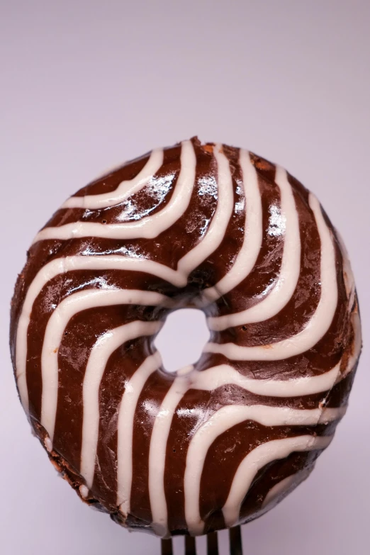 a chocolate donut with white icing on a fork, by Doug Ohlson, unsplash, patterned, made of glazed, thick lines, carved