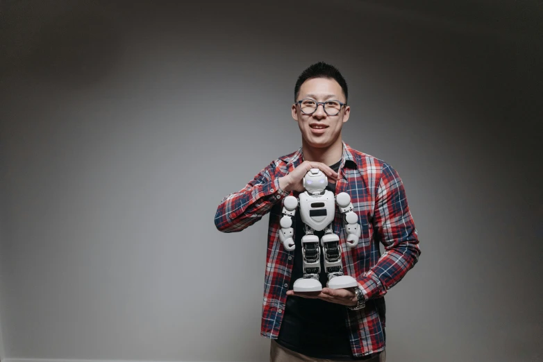 a man in a plaid shirt holding a robot, inspired by Feng Zhu, professional profile photo, avatar image, feng zhu |, professional image