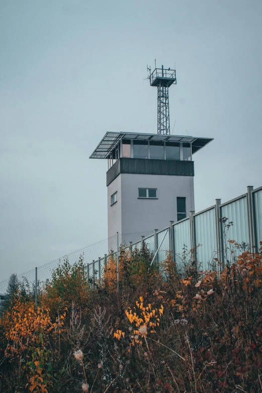 a tall tower sitting on top of a lush green hillside, by Sebastian Spreng, unsplash, graffiti, police station, airport, during autumn, square