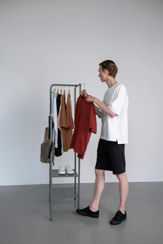 a man standing in front of a rack of clothes, by Jonas De Ro, wearing shorts and t shirt, easy to use, hyung tae, tall thin frame