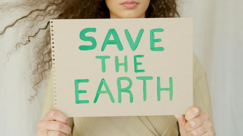 a woman holding a sign that says save the earth, trending on pexels, beige, avatar image, green, essence