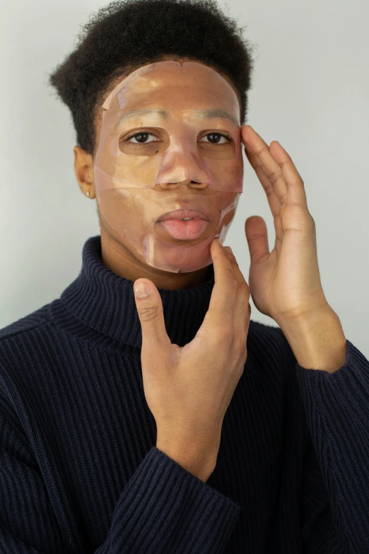 a man putting a facial mask on his face, an album cover, by Lily Delissa Joseph, trending on pexels, on clear background, silicone skin, model posing, light-brown skin