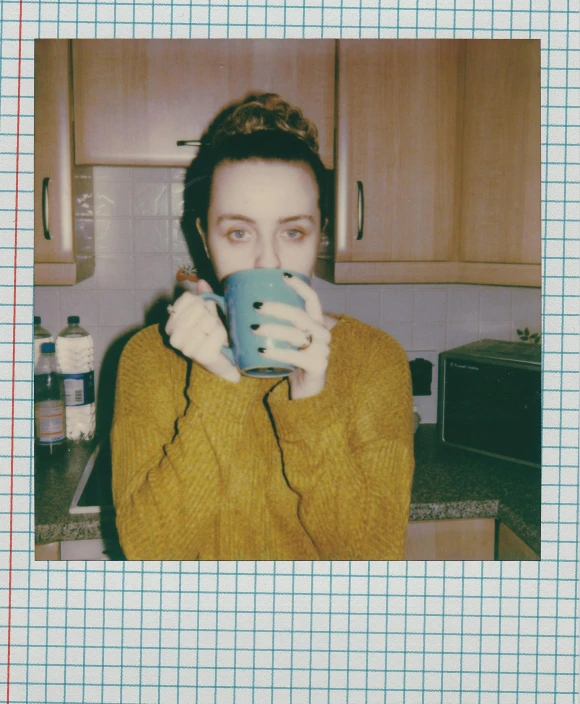 a woman holding a cup in front of her face, a polaroid photo, inspired by Elsa Bleda, saoirse ronan, vhs colour photography, eleanor tomlinson, is ((drinking a cup of tea))