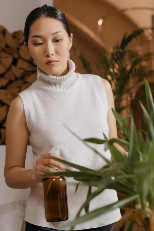 a woman standing next to a potted plant, by Julia Pishtar, trending on pexels, renaissance, sleeveless turtleneck, tea ceremony scene, drinking cough syrup, soft ambient lighting