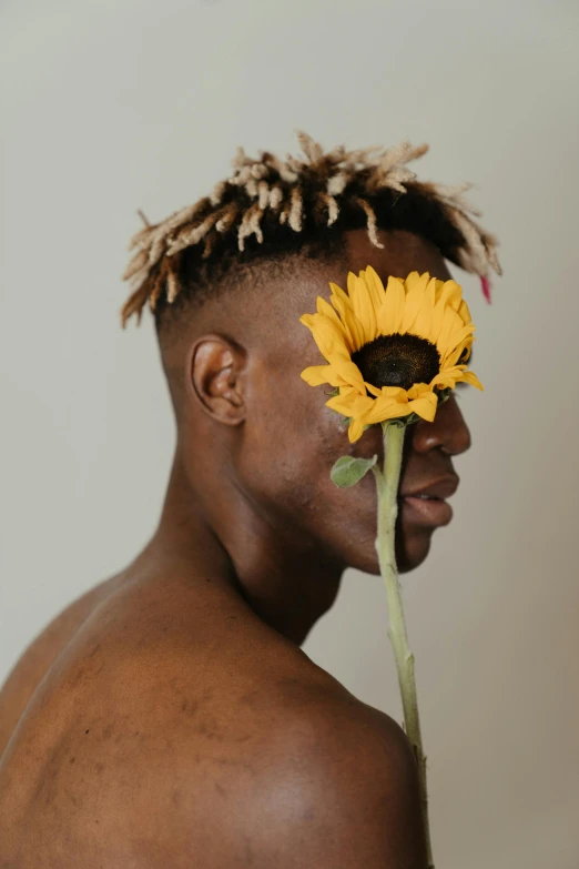 a man holding a sunflower in front of his face, an album cover, inspired by Terrell James, trending on pexels, non binary model, ( ( dark skin ) ), yasuke 5 0 0 px models, an all white human