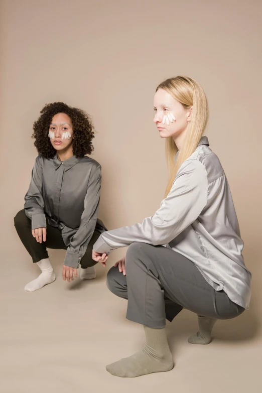 two women sitting on the ground next to each other, inspired by Vanessa Beecroft, antipodeans, gray shirt, lunar themed attire, stable diffusion ai as a human, wearing a track suit