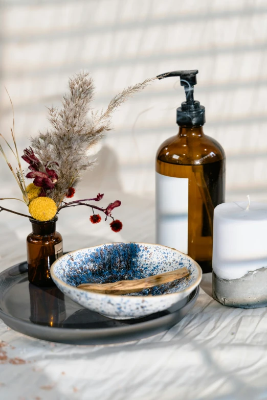 a table topped with vases filled with flowers and a soap dispenser, trending on unsplash, vanitas, maroon and blue accents, skincare, brown resin, detailed product image