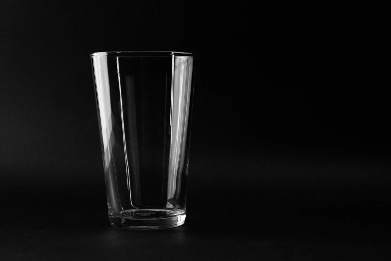 a tall glass sitting on top of a table, a black and white photo, pixabay, minimalism, black backgrounds, black square glasses, no logo, product introduction photo