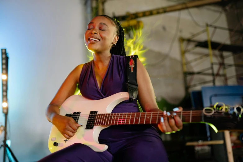 a woman that is sitting down with a guitar, by Ella Guru, happening, smiles slightly, imane anys, holding an electric guitar, performing a music video