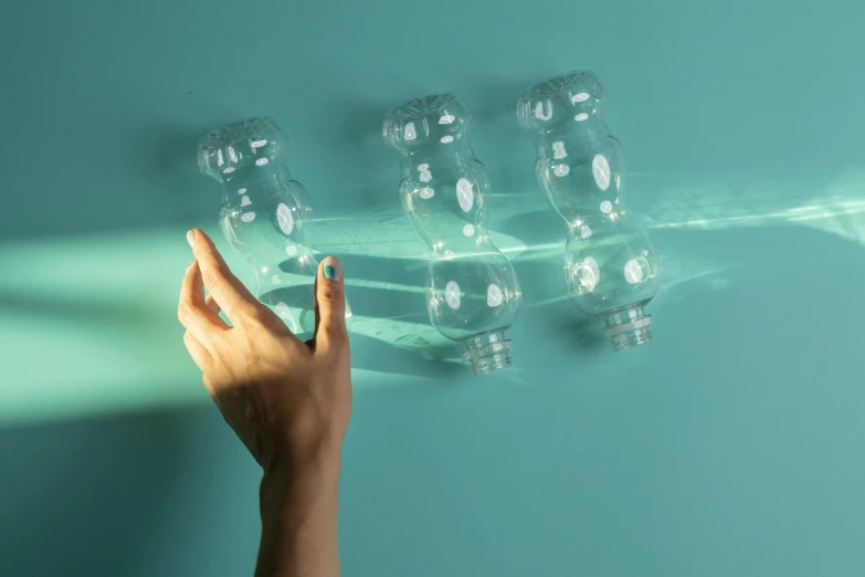 a person touching a light bulb on a wall, inspired by Leandro Erlich, pexels contest winner, plasticien, water bottles, wavy lingeries, three fourths view, teal aesthetic