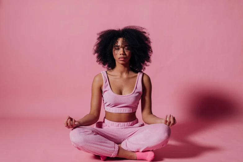 a woman sitting in the middle of a yoga pose, trending on pexels, ((pink)), afro, portrait sophie mudd, isolation