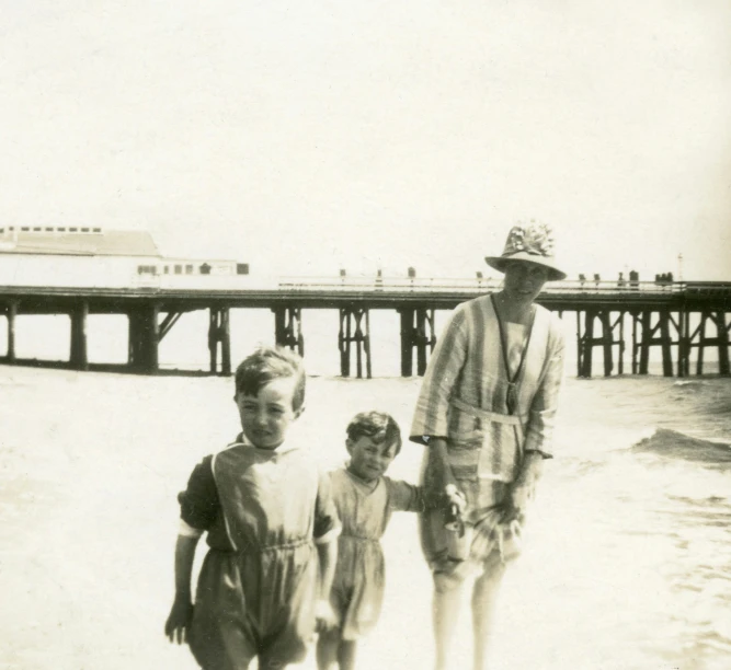 an old photo of a woman and two children on the beach, unsplash, bauhaus, boardwalk, as photograph, photograph ”