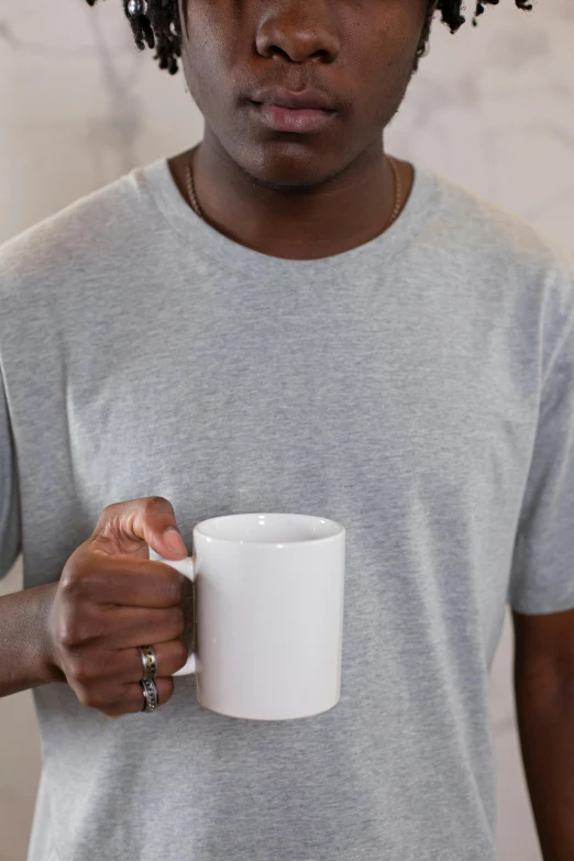 a man with dreadlocks holding a coffee mug, wearing polo shirt, light grey mist, round-cropped, detailed product image