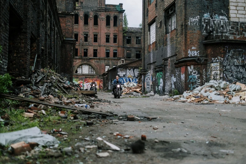 a man riding on the back of a motorcycle down a street, inspired by Thomas Struth, pexels contest winner, graffiti, abandoned warehouse, debris chips ruins, manchester, where a large