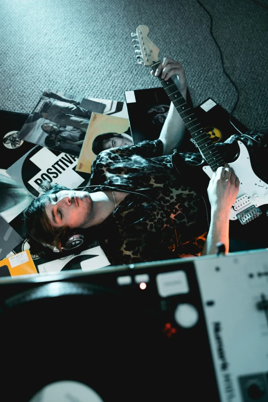 a man laying on top of a pile of music equipment, an album cover, inspired by Elsa Bleda, trending on pexels, holding electric guitar, bo burnham, focused photo, reflecting